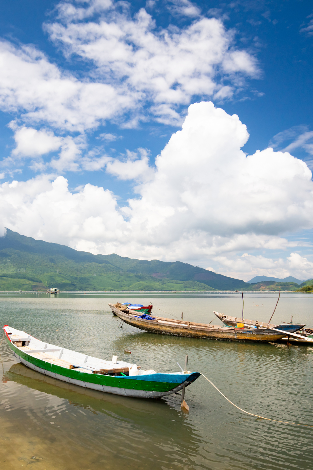 Two motor boats on water with mountain view and blue sky view in Lang Co, Vietnam