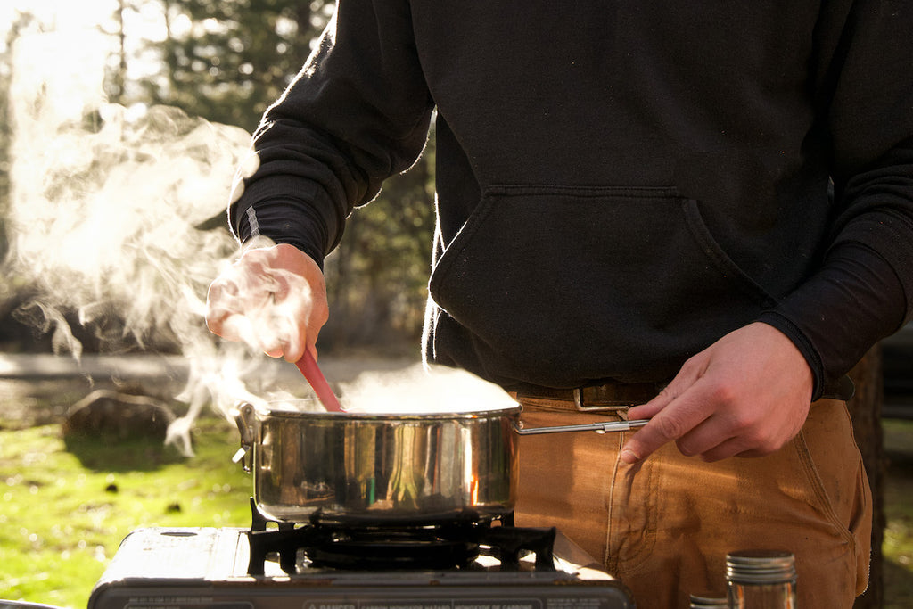 A steaming pot of food cooking on a camp stove