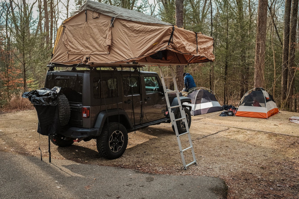 A softshell rooftop tent set up at camp