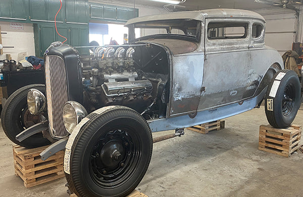 A classic silver car with the engine exposed.