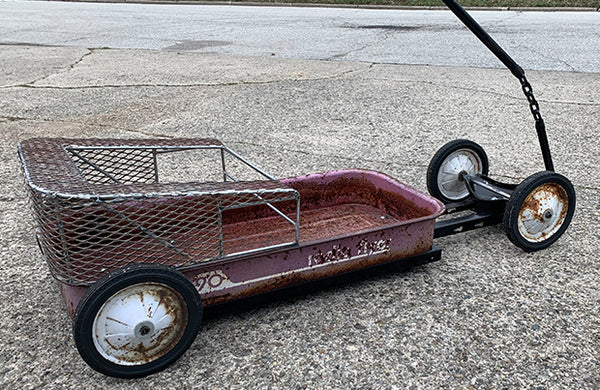 A red hand-pull wagon with a seat welded onto it.