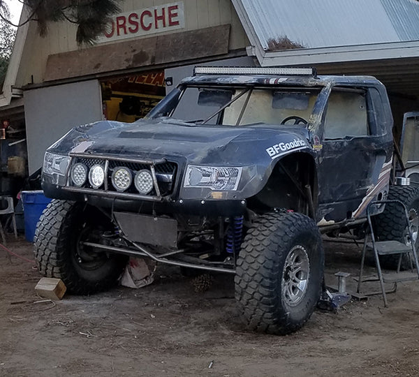 A blue off-road car parked outside a garage.