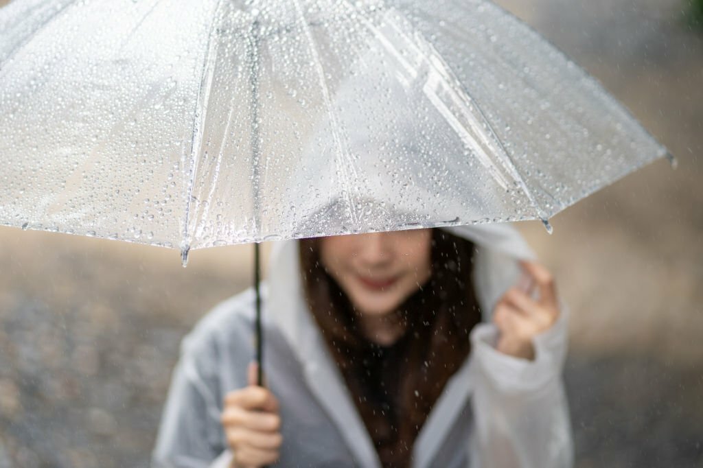 A woman carrying an umbrella in the rain to protect her eyelash extensions from moisture and humidity