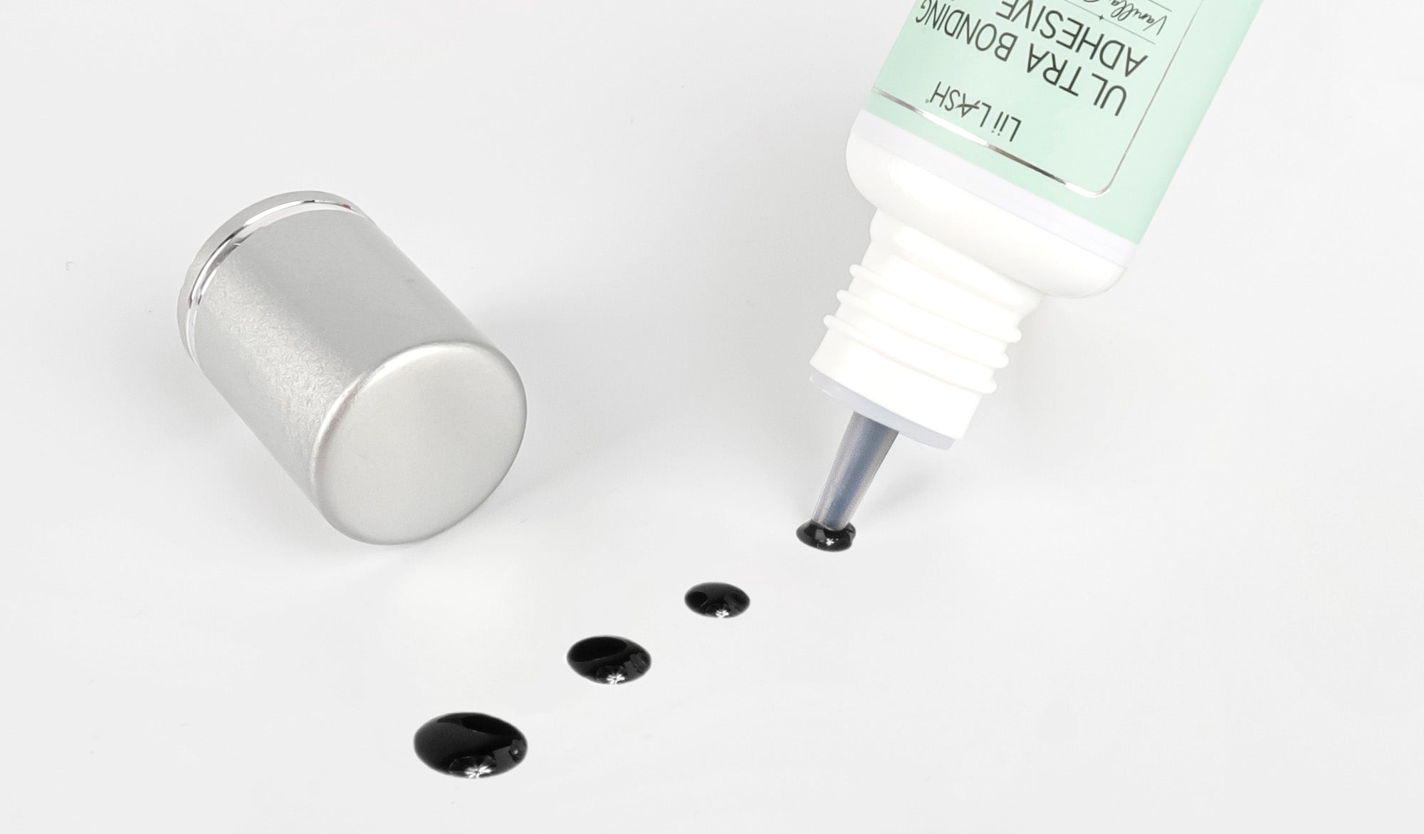 Close-up image of lash adhesive, a crucial element in eyelash extension application, with a focus on the precise applicator tip and product details