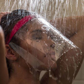 A woman taking a hot shower with a lash shield to protect her eyelash extensions from excess moisture and steam