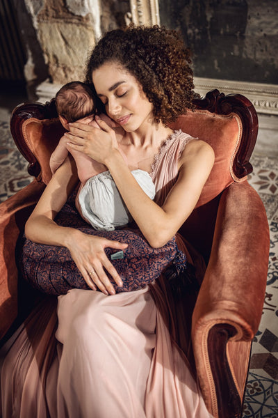 woman holding newborn with the DockATot nursing pillow in Acorn print