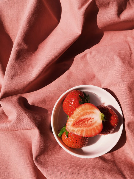 bowl of strawberries on pink sheet