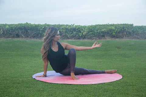 Desi Bartlett, MS CPT E-RYT Women’s Health Expert stretching outdoors on a round, red mat