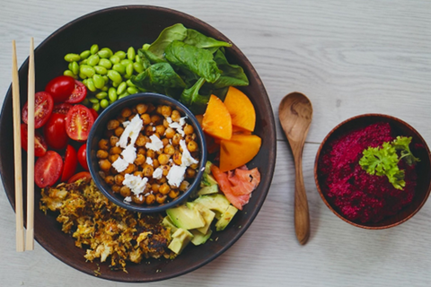 colorful lunch with assorted vegetables and chickpeas on a black plate and bowl