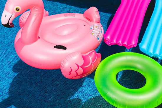 pool floats in a pool, one is a flamingo