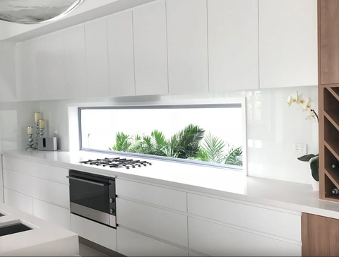 White kitchen with splashback window and plants outside