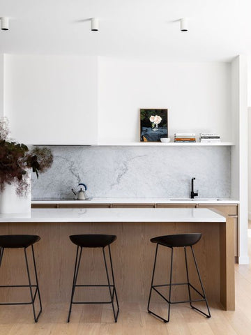 marble splashback with timber cabinets and black bar stools