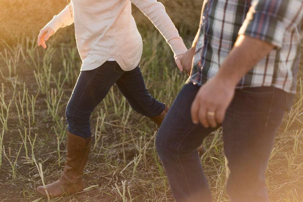 couple holding hands through the field