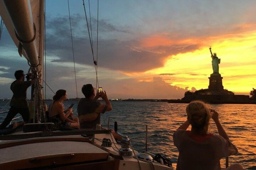 people taking picture of statue of liberty at sunset