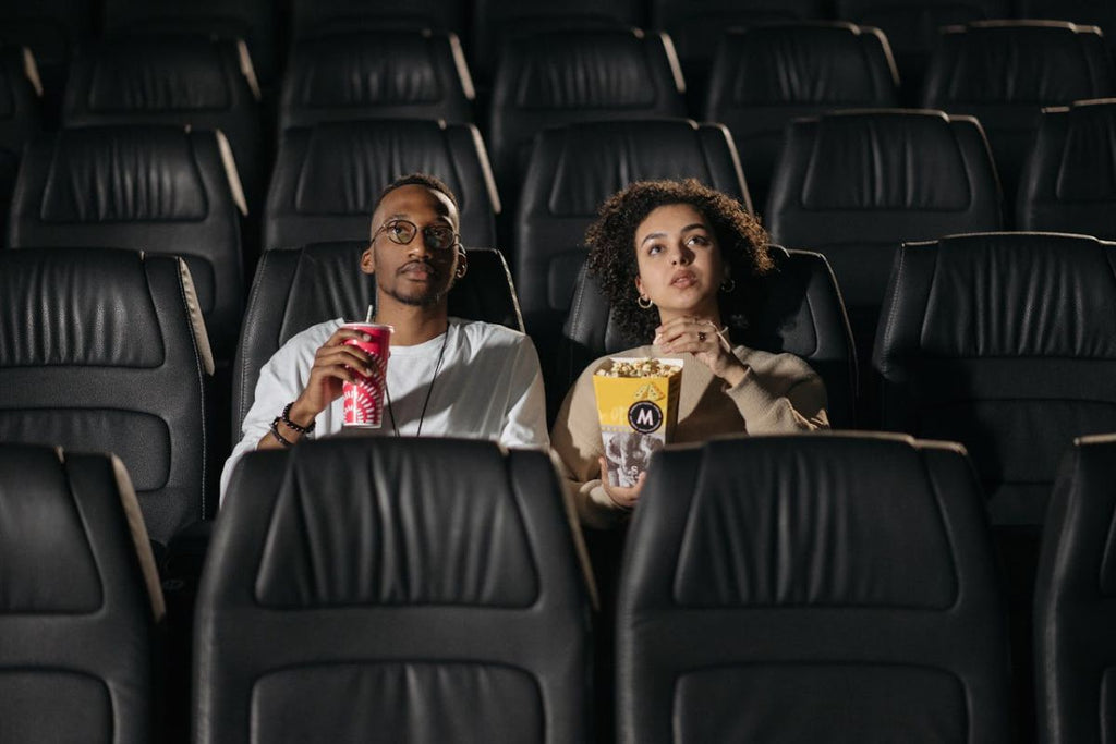 young couple at movie theatre watching film with drink and popcorn