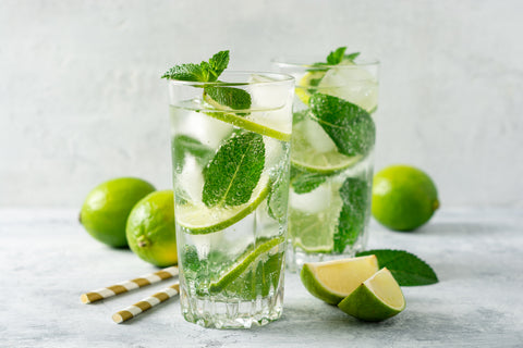 Image of two mojitos filled with lime slices and mint leaves