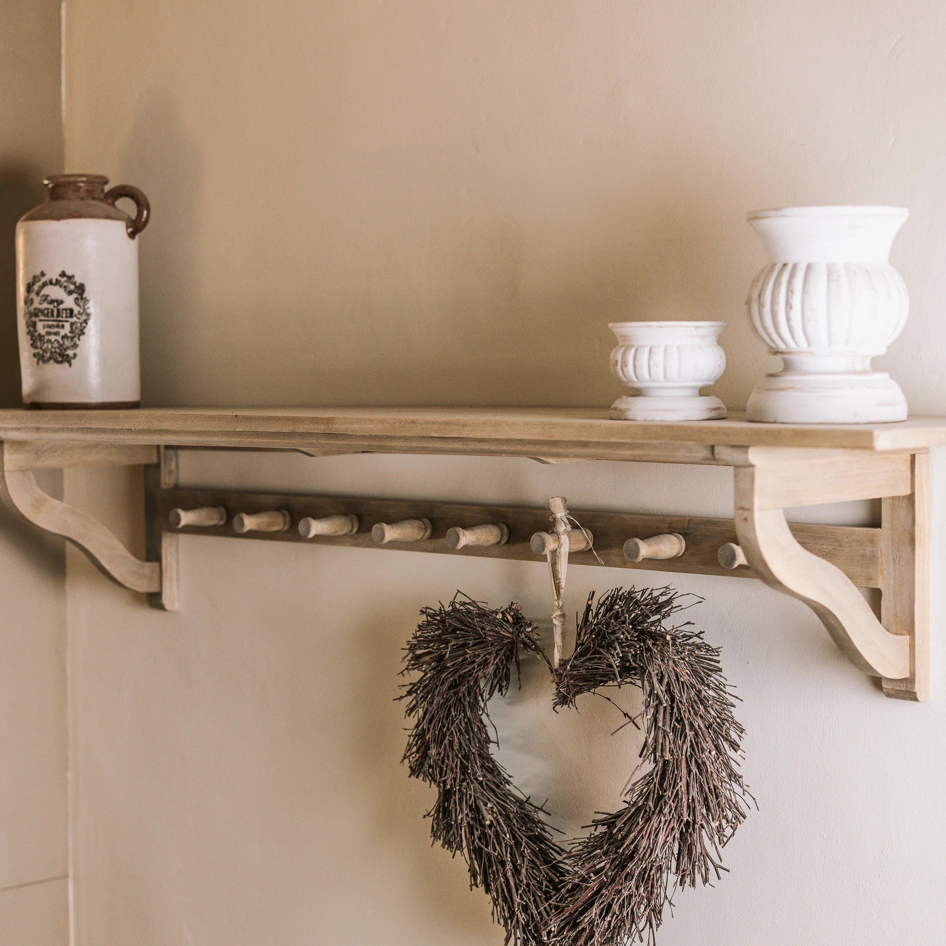 Wooden shelf with hooks and ornaments on top with a hanging heart wreath.