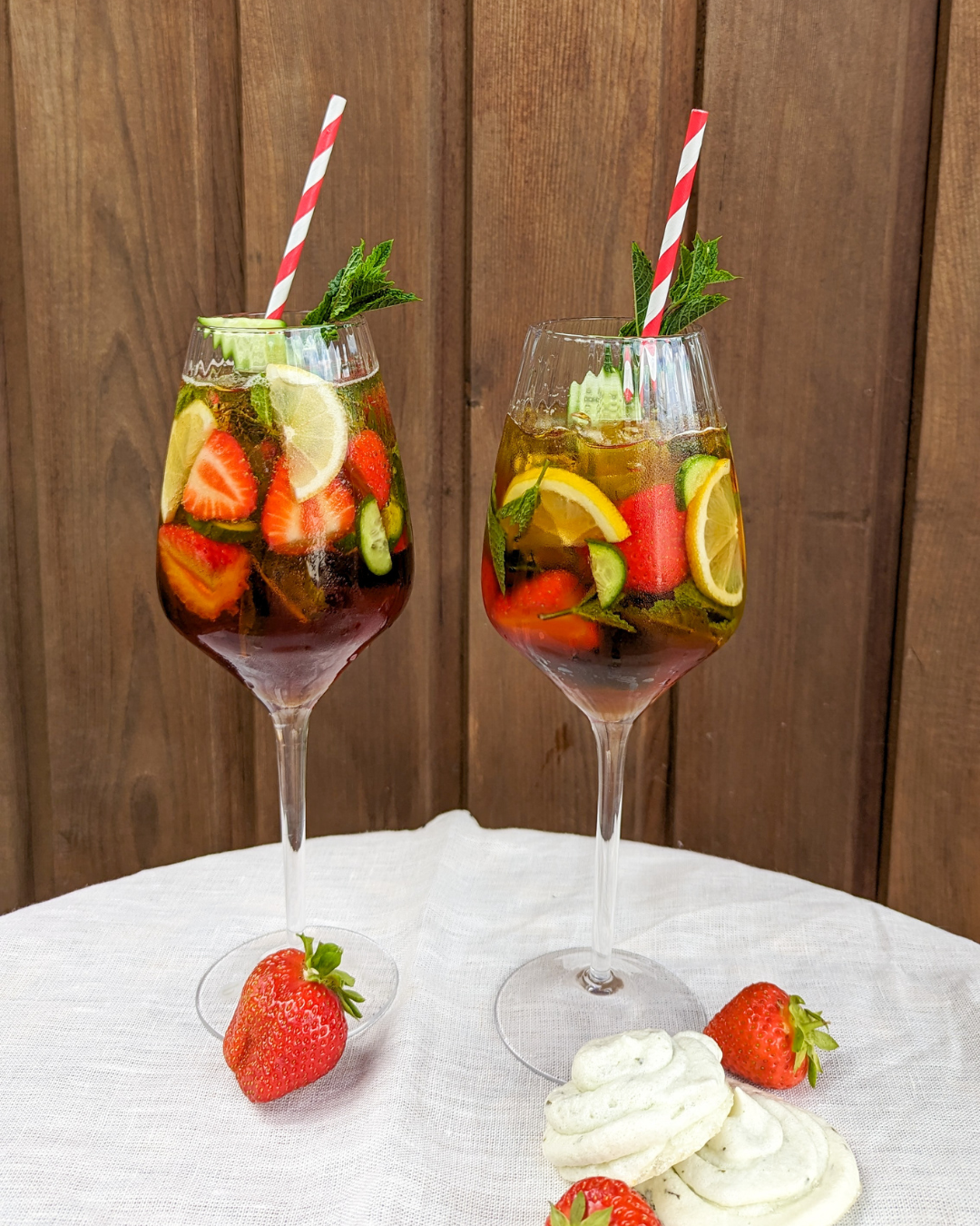 Pimms and lemonade cocktails with striped straw.