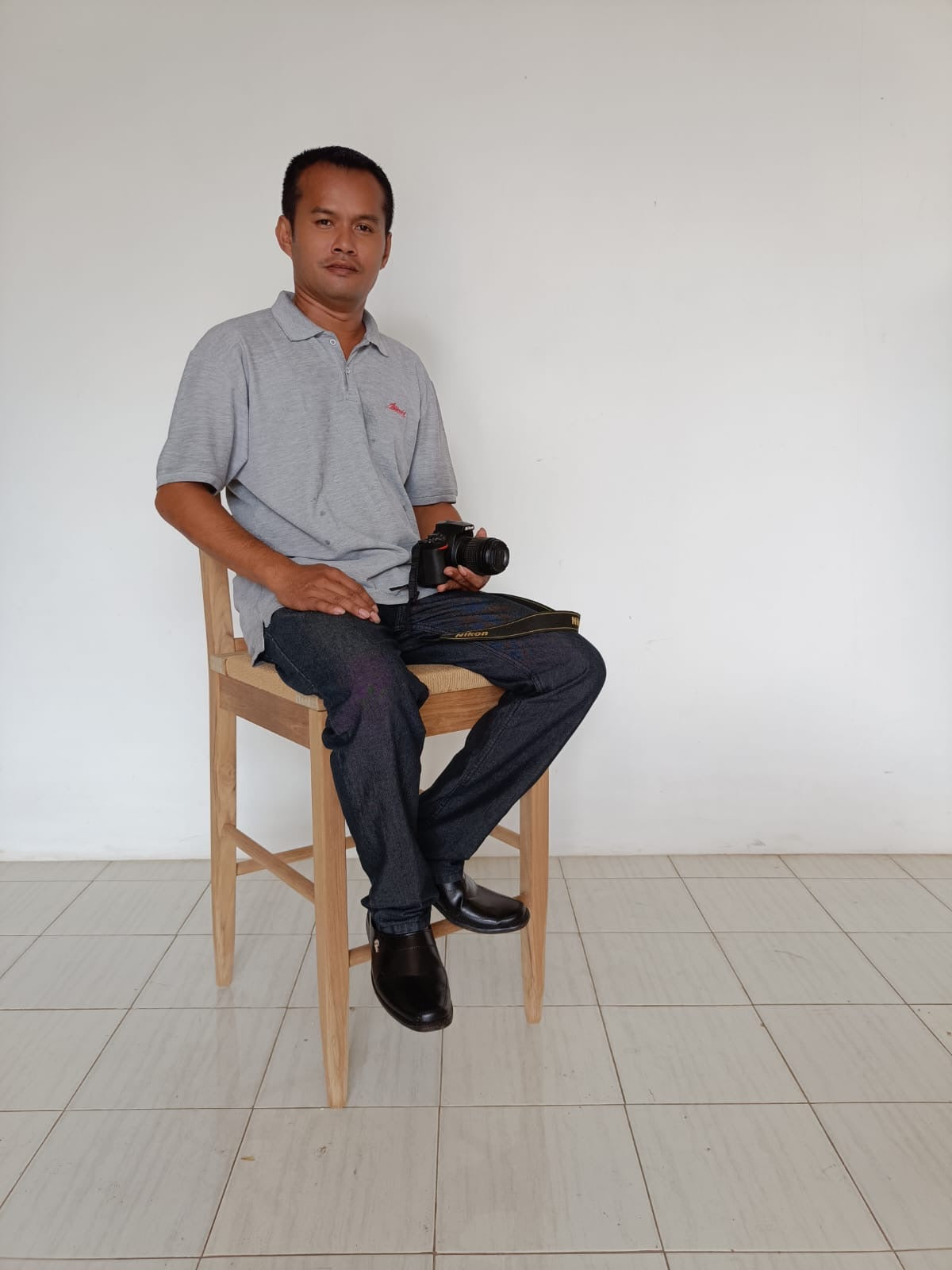 Man sitting on farmhouse wooden bar stool with camera in hand.