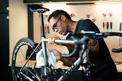 Person cleaning a bicycle with a white towel.