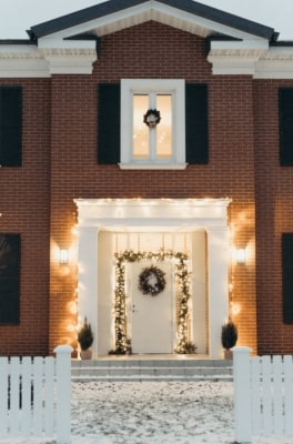 éclairage extérieur mural au niveau de l'entrée extérieure d'une maison, avec des appliques murales extérieures et une guirlande extérieure autour de la porte d'entrée