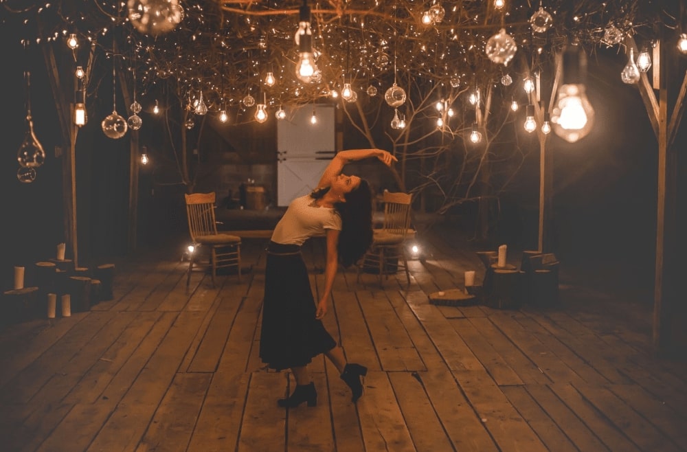 éclairage déco d'une terrasse en bois extérieure de nuit, avec danseuse au milieu