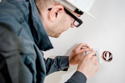 homme avec casque de chantier qui travaille sur une prise électrique