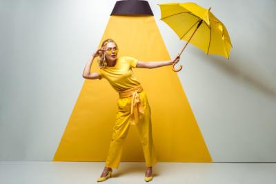 femme en jaune sous un luminaire et un parapluie jaune, représentant l'étanchéité d'une lampe
