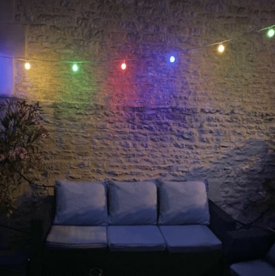 guirlande LED extérieure de type guinguette installée au niveau d'un mur en pierre extérieur de terrasse