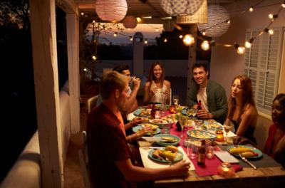 repas convivial sur une terrasse éclairée par des guirlandes LED au plafond