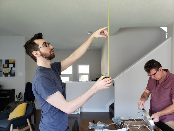 deux hommes qui préparent l'installation d'un luminaire suspendu