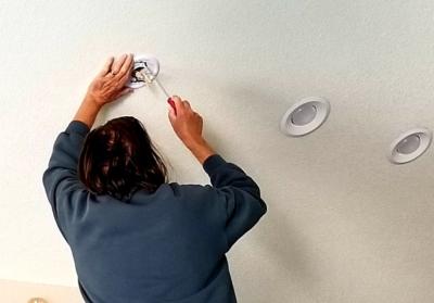 électricien qui installe des spots LED au plafond d'un bureau