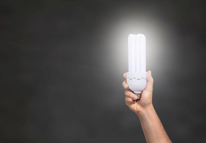 ampoule tenue d'une main, diffusant une lumière intense