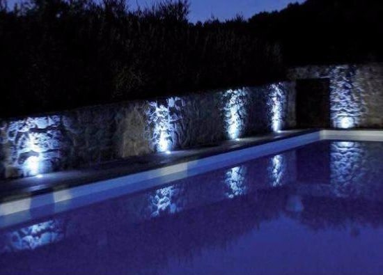 spots LED extérieurs encastrés dans la terrasse d'une piscine de nuit