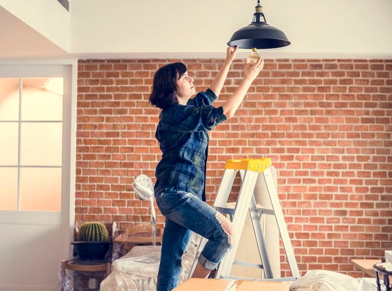 femme qui remplace une ampoule au plafond