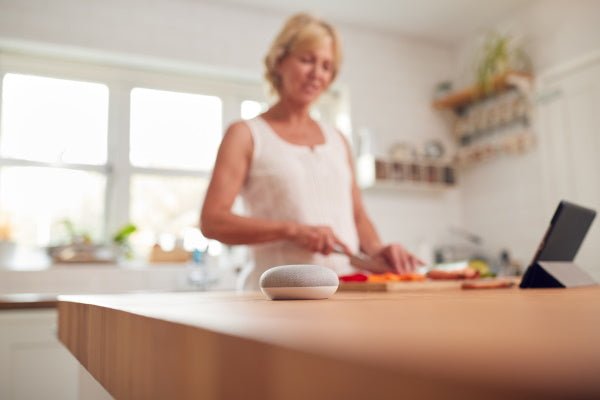 femme utilisant une enceinte connectée pendant qu'elle cuisine