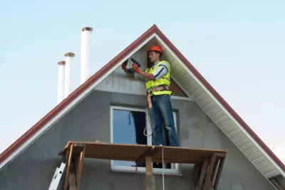 homme qui installe un spot extérieur encastrable sous une toiture de maison