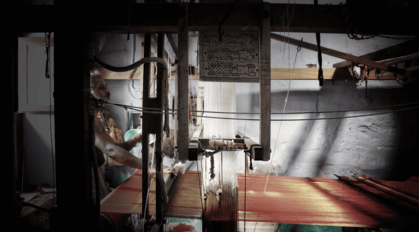 A male weaver waving a saree on a handloom at his home