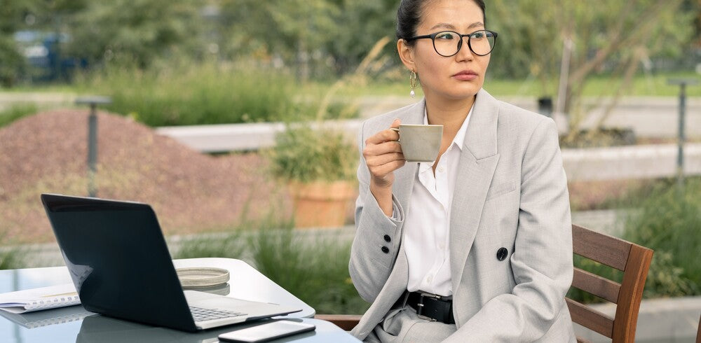une femme entrain de boire du thé sur son bureau pour en profiter des bienfaits au quotidien