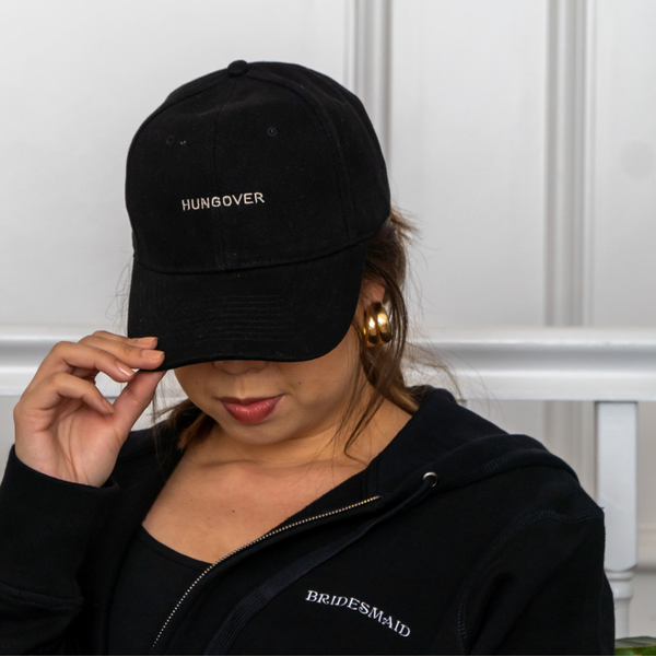 woman wearing black baseball cap embroidered with 'hungover' slogan in white