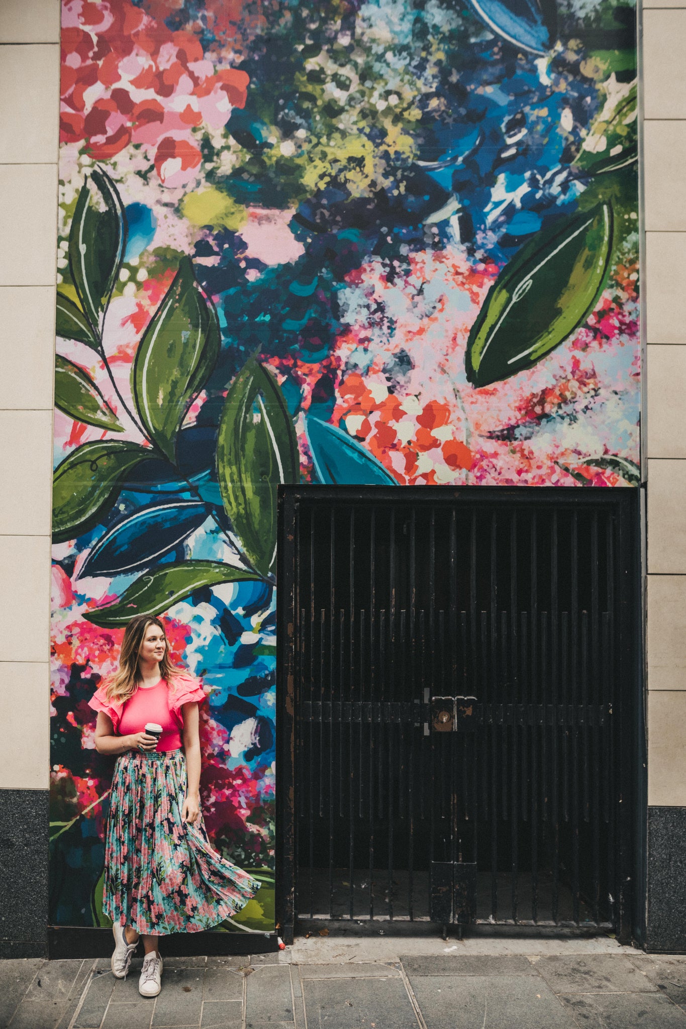 abstract artist stood in front of colourful floral mural in liverpool