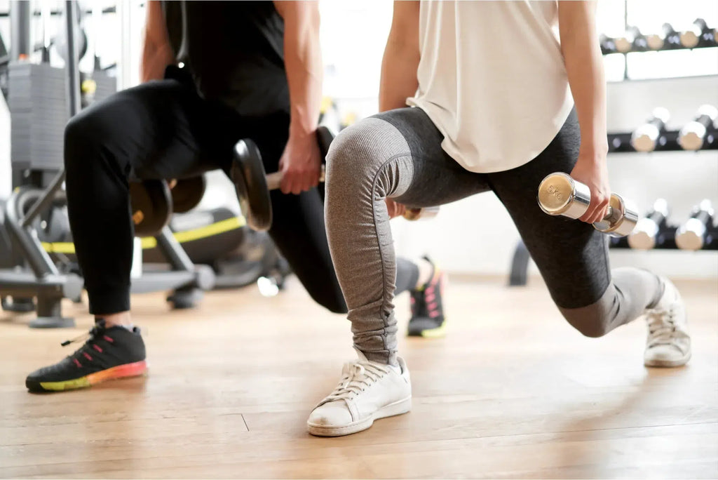 Couple Demonstrating Dumbbell Forward Lunge