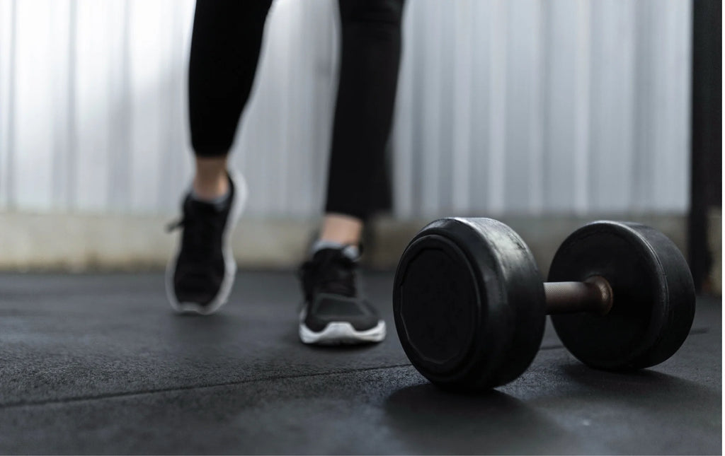 Round dumbbells at gym with woman's feet in the image