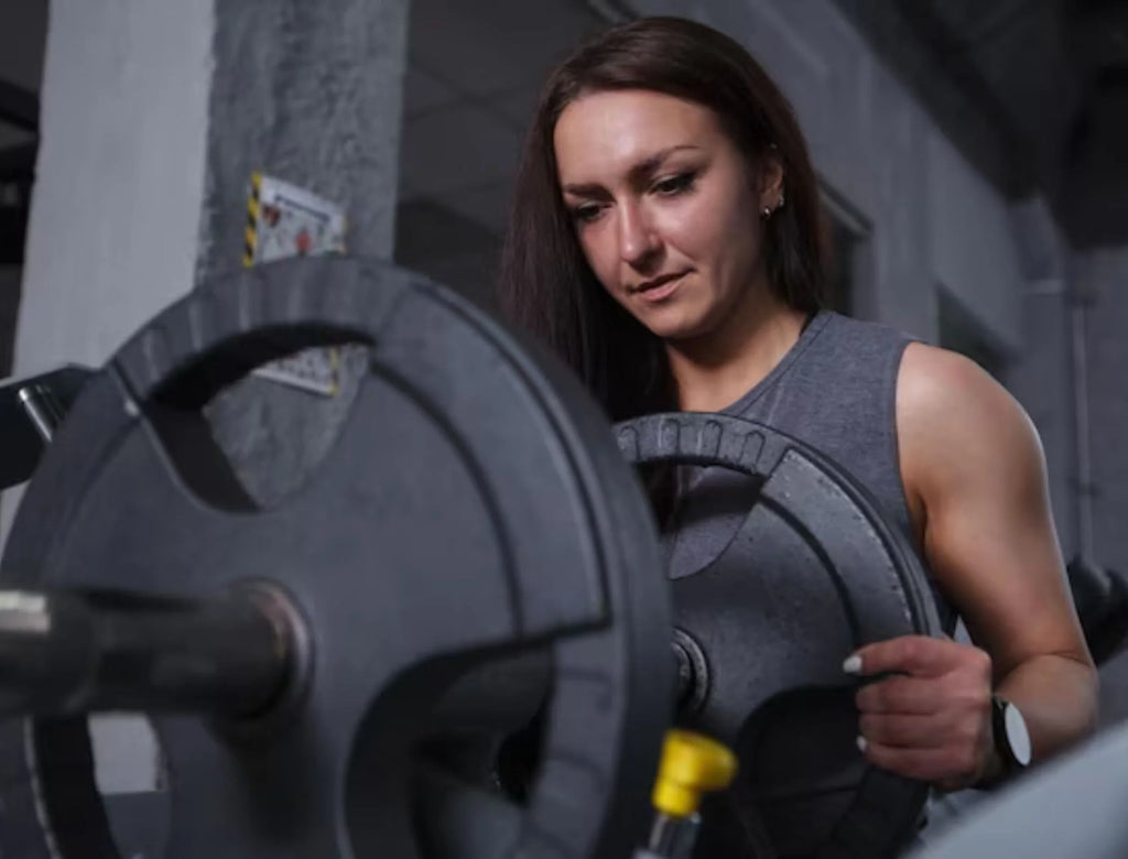 girl adding weight plates to a barbell