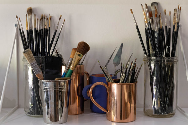 Paint brushes in jars on a shelf