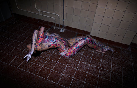 Image of Nina Burri, the Body Painted Snake Woman, Striking a Pose on a Tile Floor