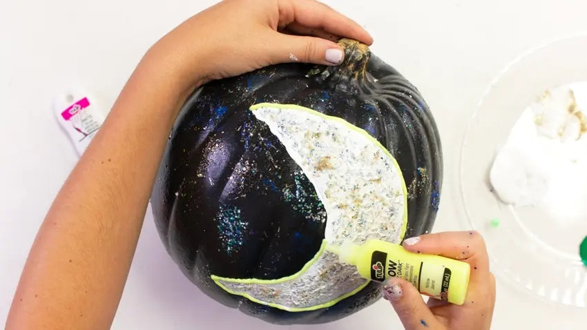 Create crescent moon design with white, glitter and glow paints