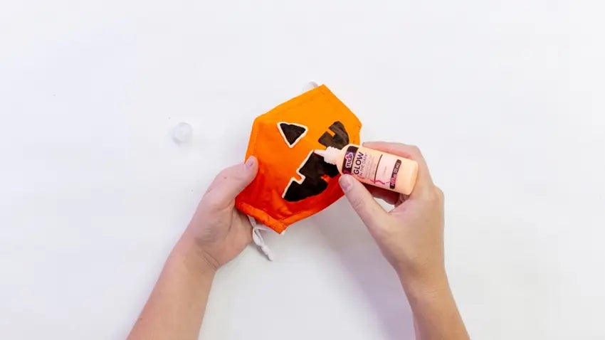 Outline the jack-o-lantern face with Glow in the Dark Dimensional Fabric Paint