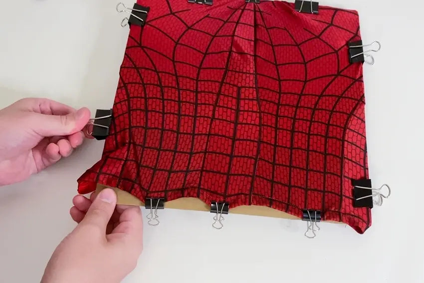 Position Spider-Man mask on cardboard and secure with clips