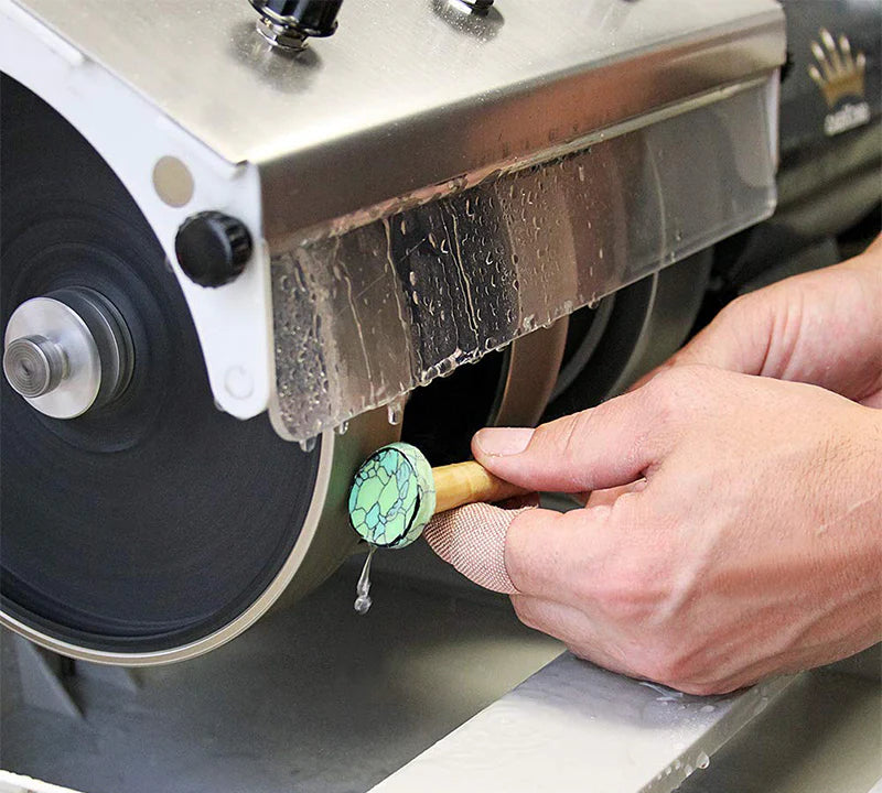 close up of hands shaping and grinding a cabochon shape on a cabbing machine to shape, grind and polish a green gemstone